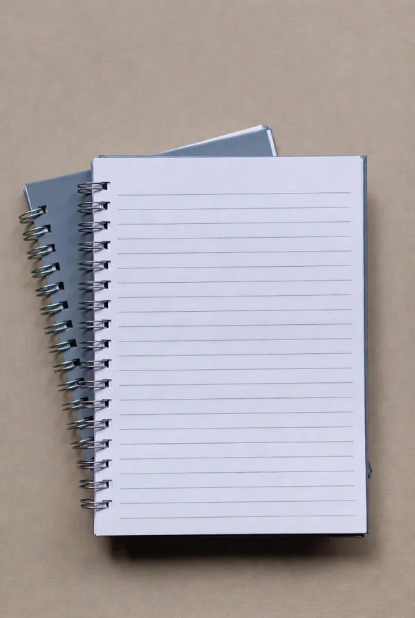 Two spiral bound notebooks with lined pages on a beige desk